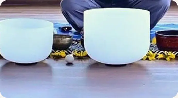 A white crystal singing bowl and Tibetan bowls on the floor