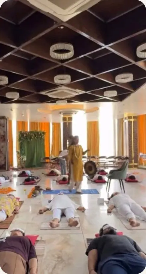 Yatri resting on mats in a bright hall while the facilitator walks between them