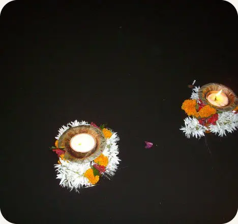 Floating diyas ringed with marigold and jasmine on dark water
